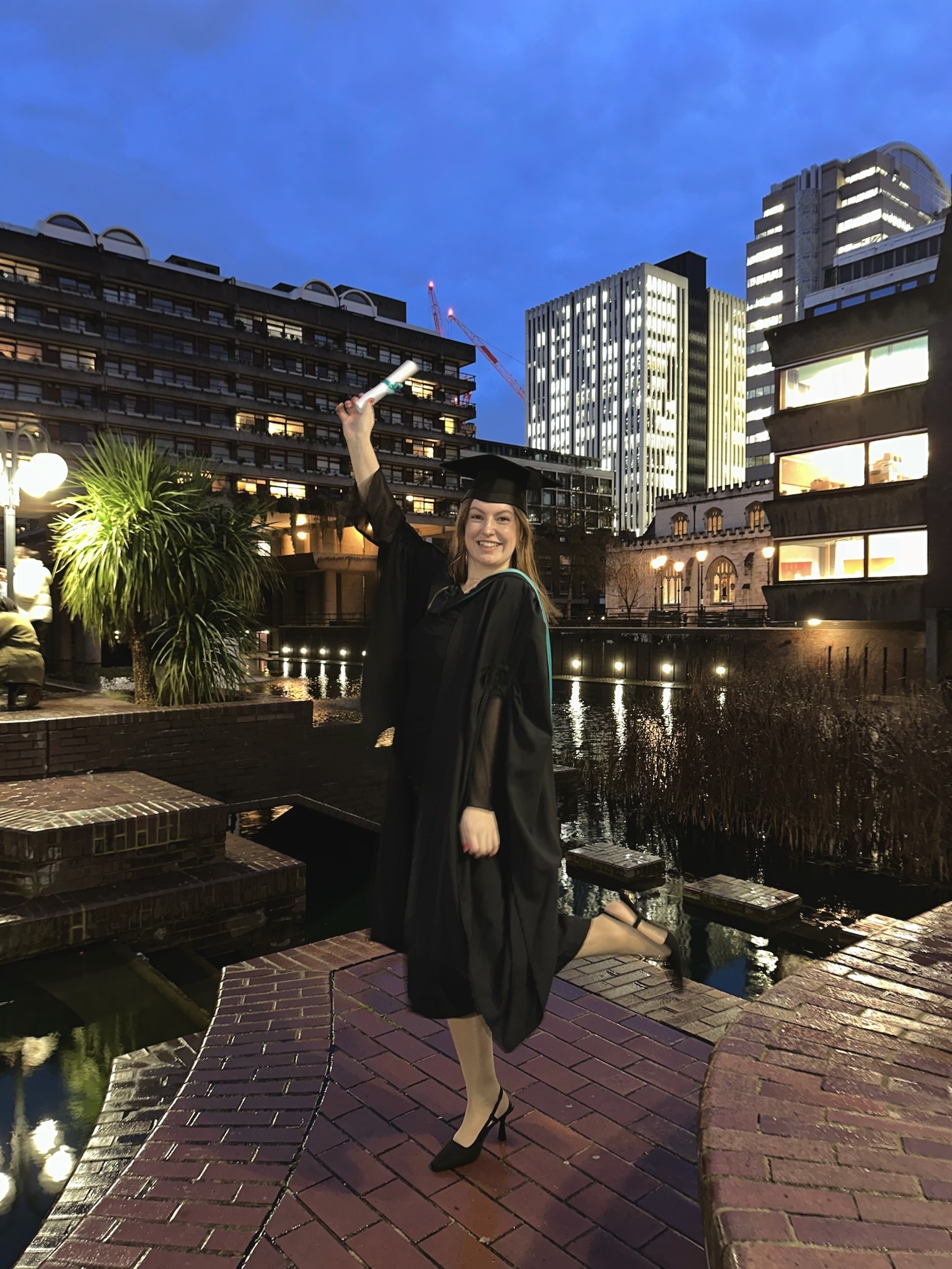 Nicole Sandrew standing in a cap and down holding her diploma in her hand.